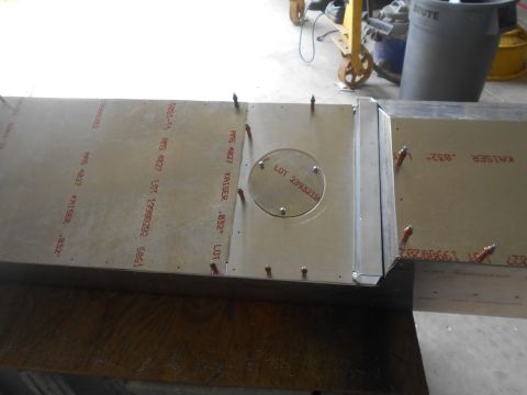 1992 Ford Bronco - A close-up view of two pieces of aluminum sheeting with red stenciled text and markings. One piece has a circular cutout with fasteners, an…
