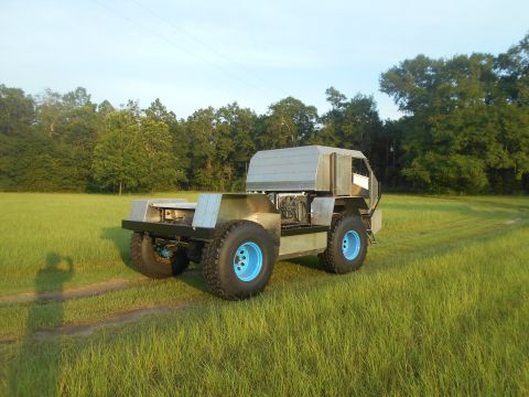1992 Ford Bronco - A custom-built, four-wheel-drive vehicle with a silver metallic body sits in a grassy field with trees in the background. The vehicle featu…