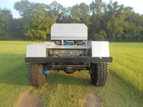 1992 Ford Bronco - The rear view of a custom-built vehicle, possibly a truck or utility vehicle, with large off-road tires and a metallic body. The vehicle is…