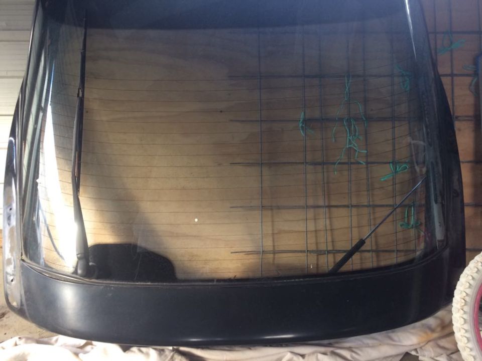 Rear hatch glass with defroster grid, wiper, and green string decorations.