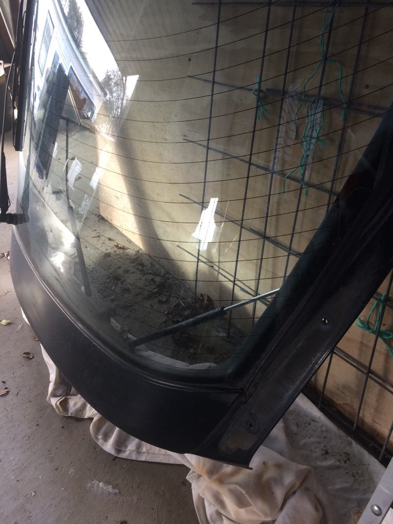 Rear car window with defroster lines, resting on a white cloth.