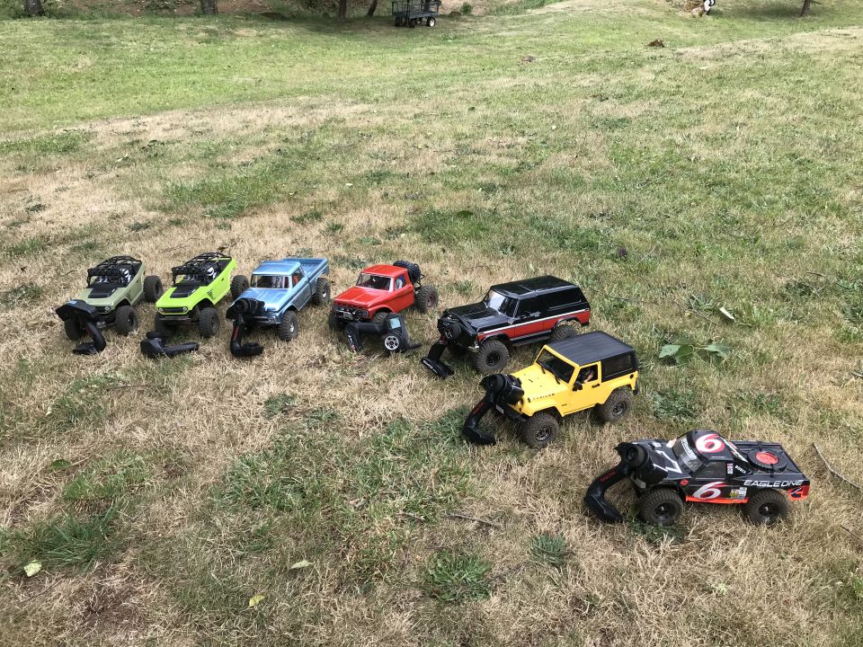 Several remote-controlled off-road vehicles on a grassy field.
