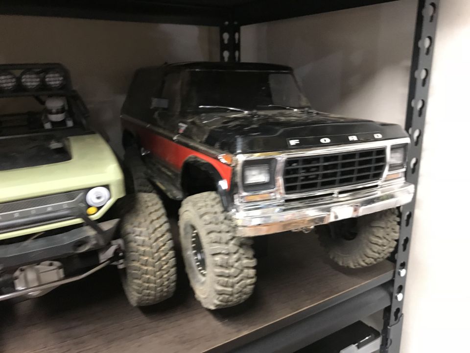 Black and red 1980s Ford Bronco with chrome details, parked on a shelf.