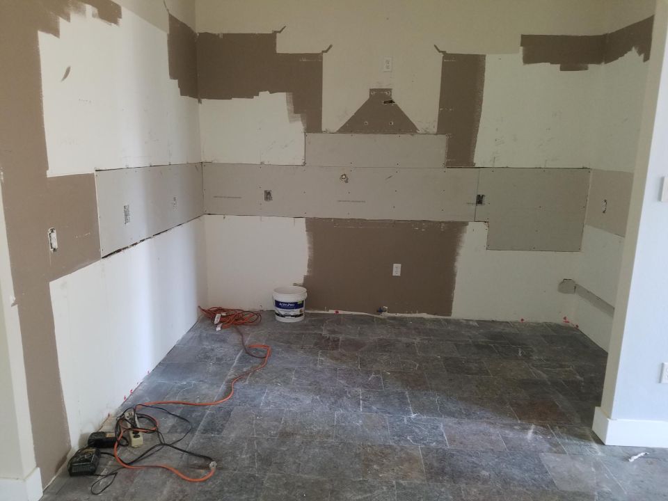 Photo of a room interior with partial drywall and bare floor during renovation