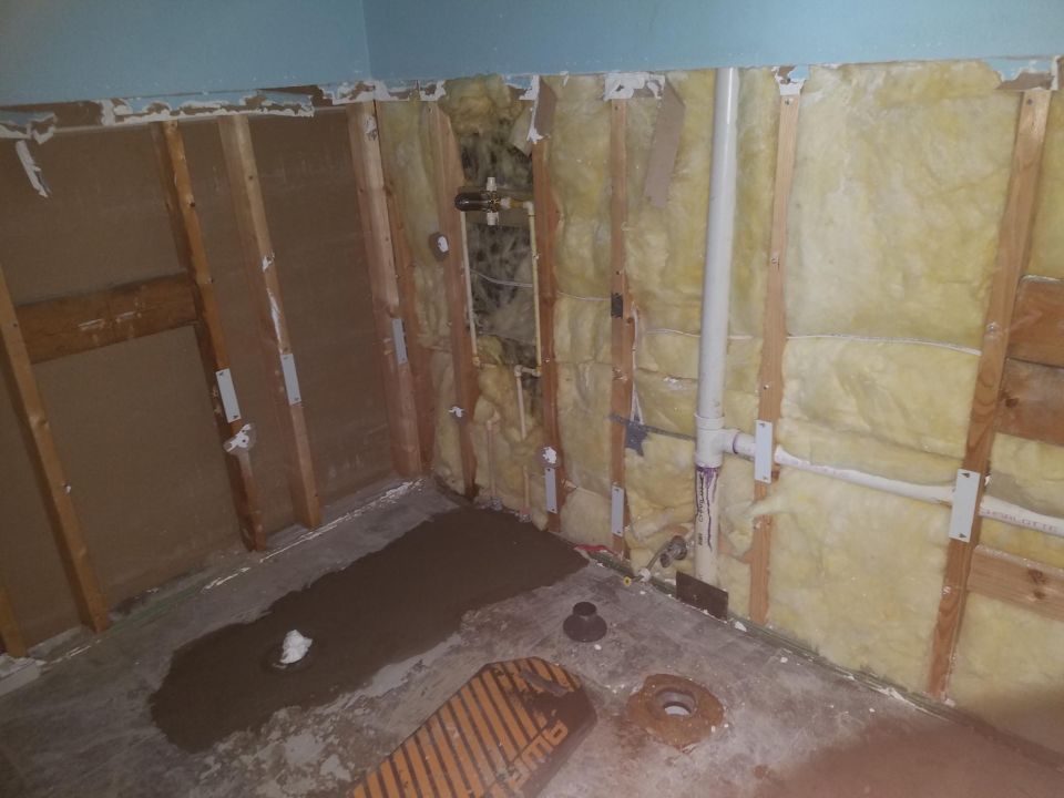 Photo of an open wall showing insulation and plumbing during renovation