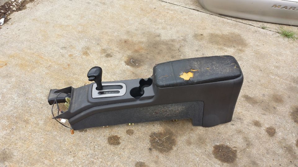 Car automatic transmission shifter console with torn armrest on concrete