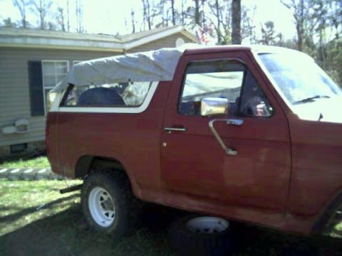 1986 Ford Bronco - This 1986 Ford Bronco is parked outside a house with a tarp covering its top.