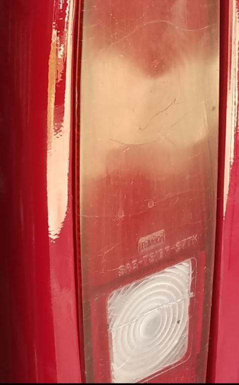 1968 Ford Bronco - A close-up view of a red vehicle's taillight assembly, showing a clear lens with visible text and a textured reflector. The lens has severa…