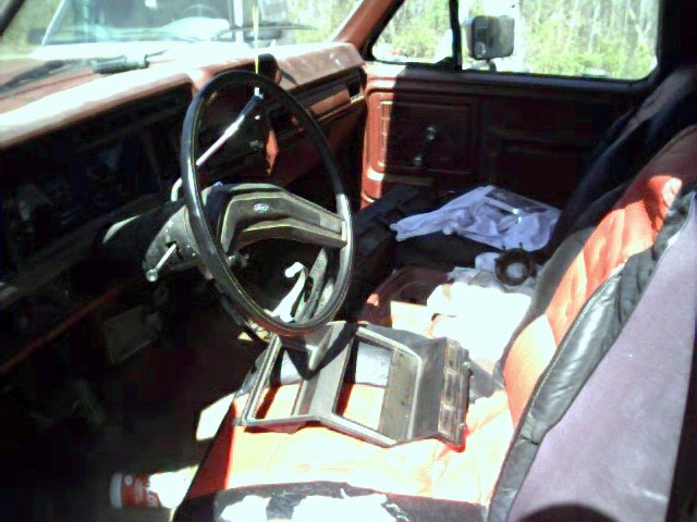 Interior of a red 1980s Ford truck, showing dashboard, steering wheel, and seats