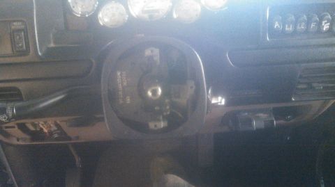 1992 Ford Bronco - Dim interior shot of a tan/beige truck dash with the steering wheel removed, exposing the splined steering shaft and a round steel wheel ad…