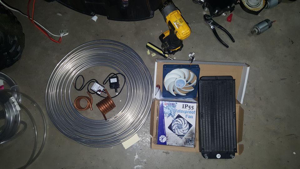 Computer water cooling parts: tubing, pump, radiator, fan, and tools on concrete floor.