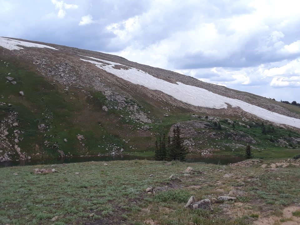 Mountain landscape with a lake and snow on a cloudy day.