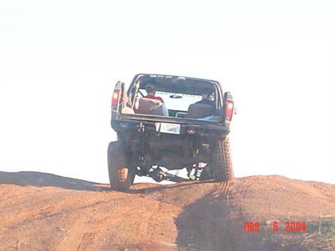 1978 Ford Bronco - A modified off-road vehicle navigates a steep dirt incline with two occupants visible.