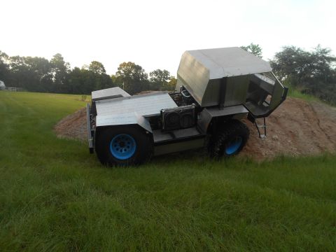 1992 Ford Bronco - A custom-built, amphibious-looking vehicle with a silver, boxy cab and a flatbed sits on a dirt mound surrounded by grass. The vehicle feat…