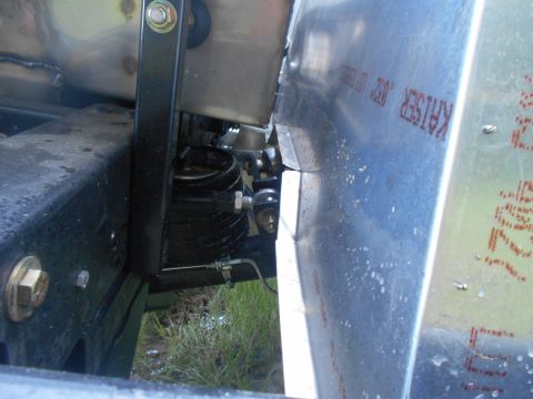 1992 Ford Bronco - A close-up view of the suspension and frame of a vehicle, showing a black metal bracket holding a silver tank, with a black coil spring and…
