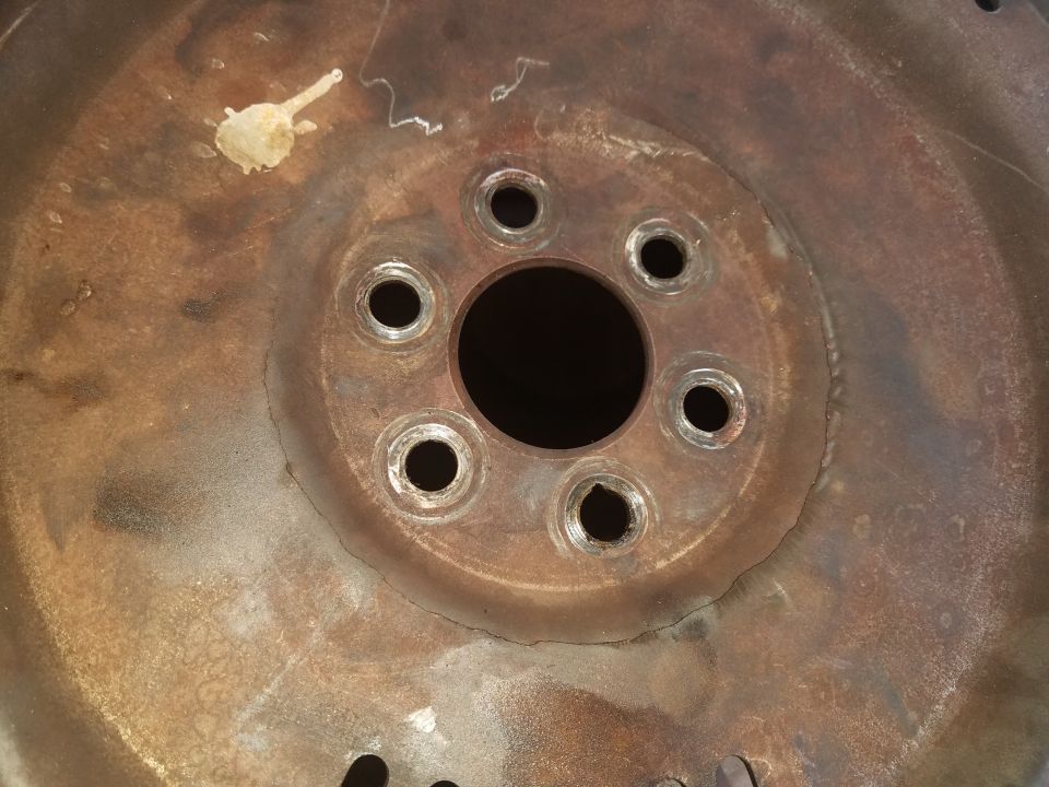 Rusty wheel hub with six bolt holes and a central circular opening