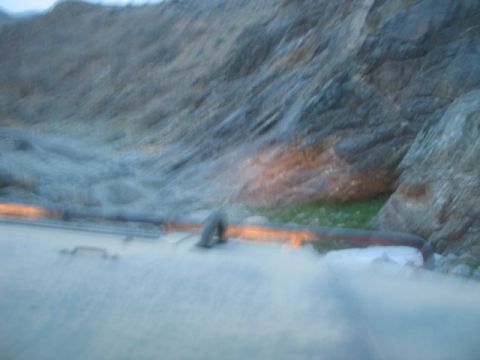 1981 Ford Bronco - The interior of a vehicle is visible, with the dashboard and headlights illuminated against a rocky, outdoor backdrop.