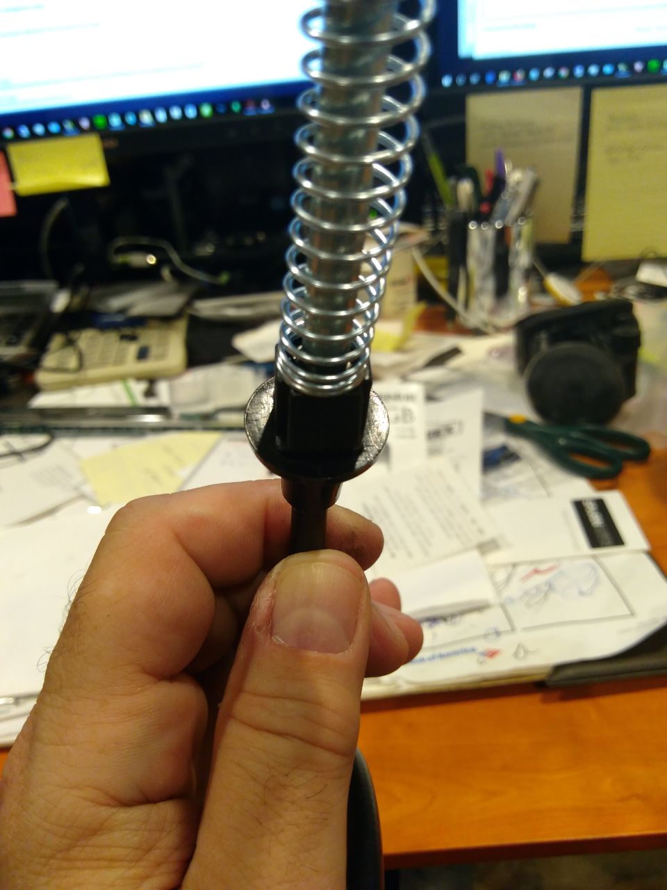 Hand holding a metal cable with a coiled spring and a washer