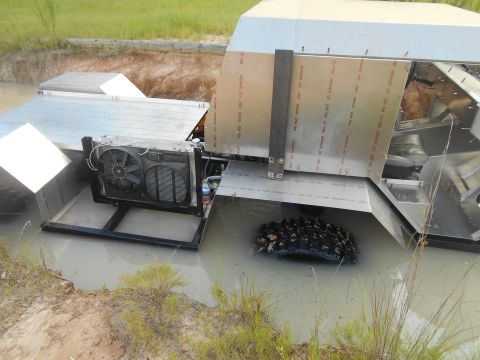 1992 Ford Bronco - A custom-built vehicle, possibly an amphibious vehicle, is partially submerged in muddy water. The vehicle features a large fan and radiato…