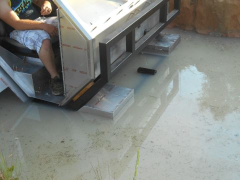 1992 Ford Bronco - A person sits in the driver's seat of a custom-built vehicle, partially submerged in murky water. The vehicle appears to be constructed fro…