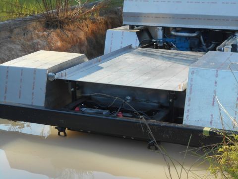 1992 Ford Bronco - A custom-built aluminum watercraft with a visible engine and battery is partially submerged in murky water. The vessel features a flat deck…