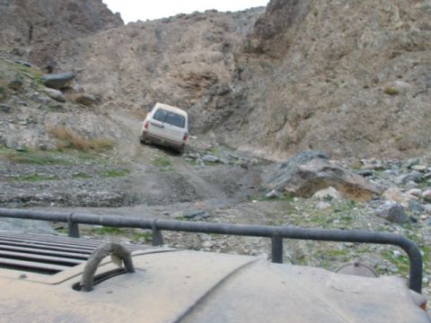 1981 Ford Bronco - A white van navigates a challenging rocky mountain pass, with another vehicle in the foreground.