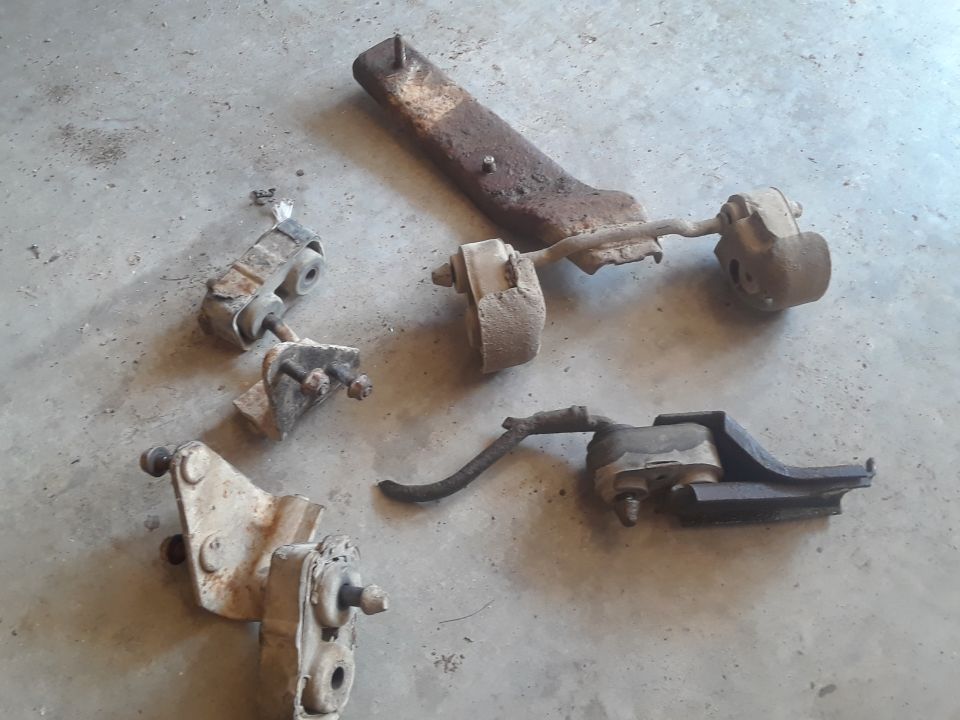 Several rusty engine mounts and brackets on a concrete floor