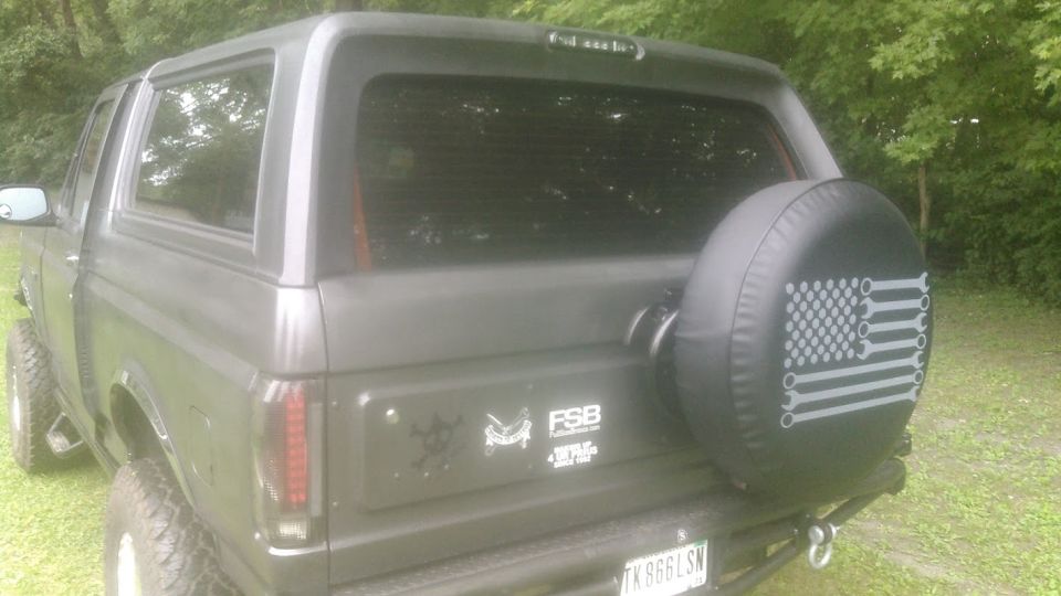 Dark gray SUV with a spare tire cover featuring a wrench American flag design.