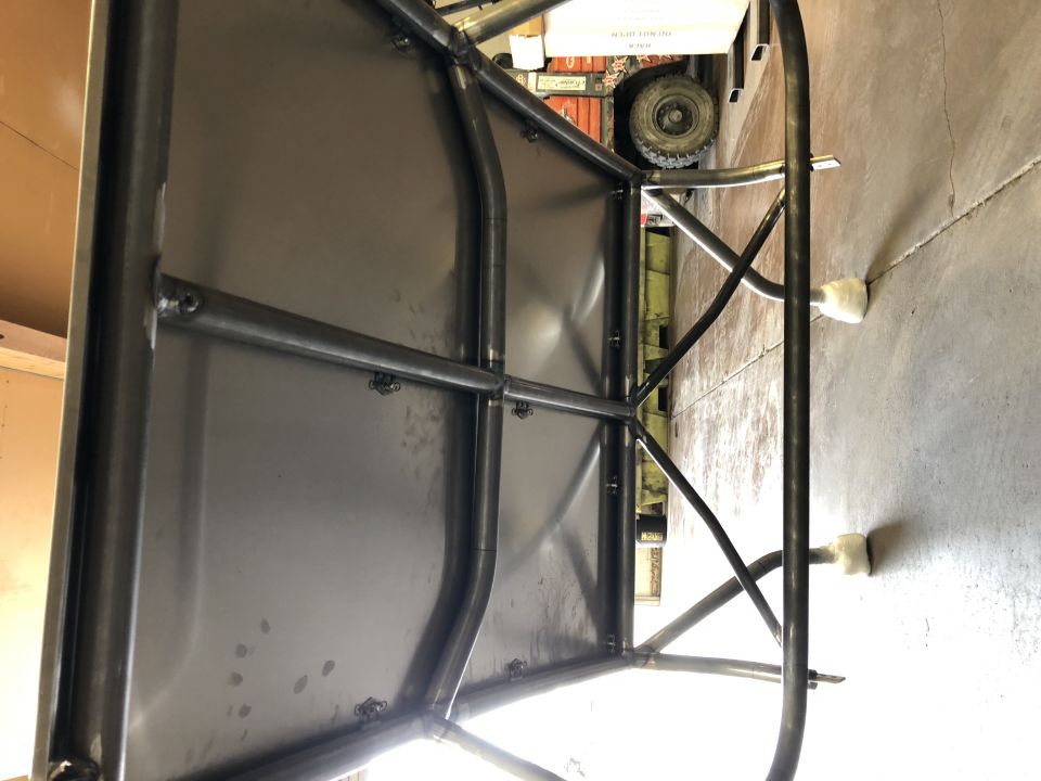 Close-up of a custom metal frame and bed of an off-road vehicle in a garage.