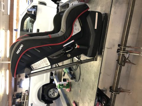 2018 Polaris RANGER - A Recaro car seat is shown mounted on a metal frame, with a white truck visible behind it.