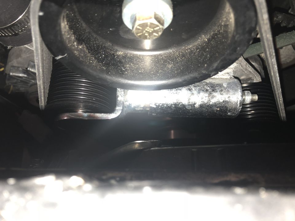 Close-up of a supercharger belt tensioner pulley with ribbed belt