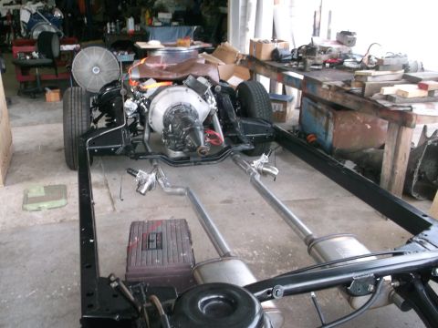 1967 Ford Galaxie - A vehicle chassis is partially assembled with its engine and exhaust system in a cluttered garage.