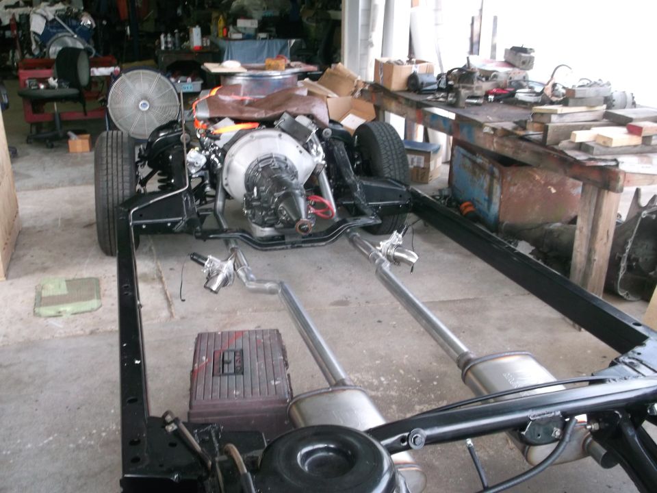 Car frame with engine and dual exhaust system in a workshop