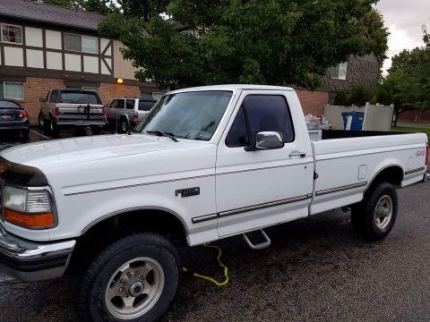 1995 Ford Bronco - White 1995 Ford F-250 pickup truck parked in a lot. Other vehicles are visible in the background.