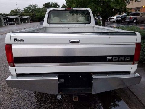 1995 Ford Bronco - Rear view of a white Ford pickup truck with a chrome bumper and a black stripe on the tailgate.