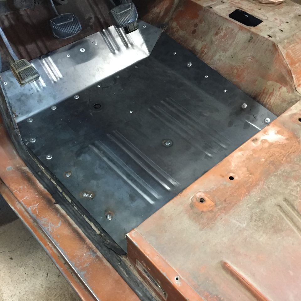 Bare metal replacement floor pan installed in a vehicle cab