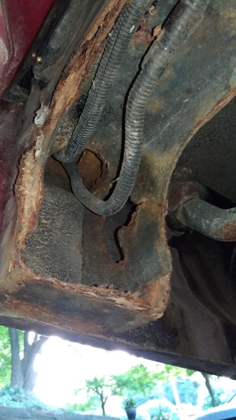 1996 Ford Bronco - The undercarriage of a vehicle shows significant rust damage and exposed wiring.
