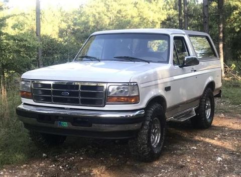1996 Ford Bronco - A white 1996 Ford Bronco is shown from a three-quarter front view, parked outdoors on a dirt path.