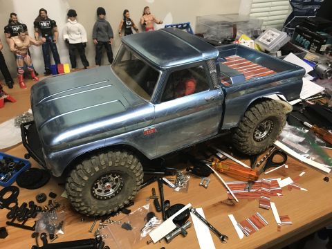 1989 Ford Bronco - RC model truck with parts and action figures scattered around on a table.