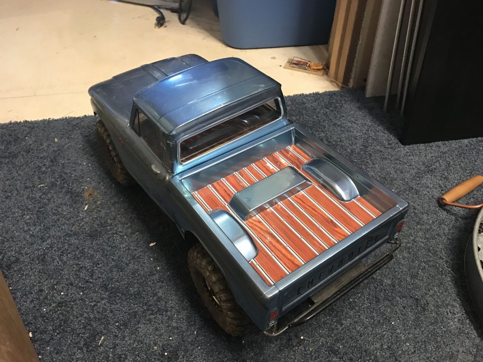 Blue toy truck with wood-grain bed, seen from a 3/4 front angle