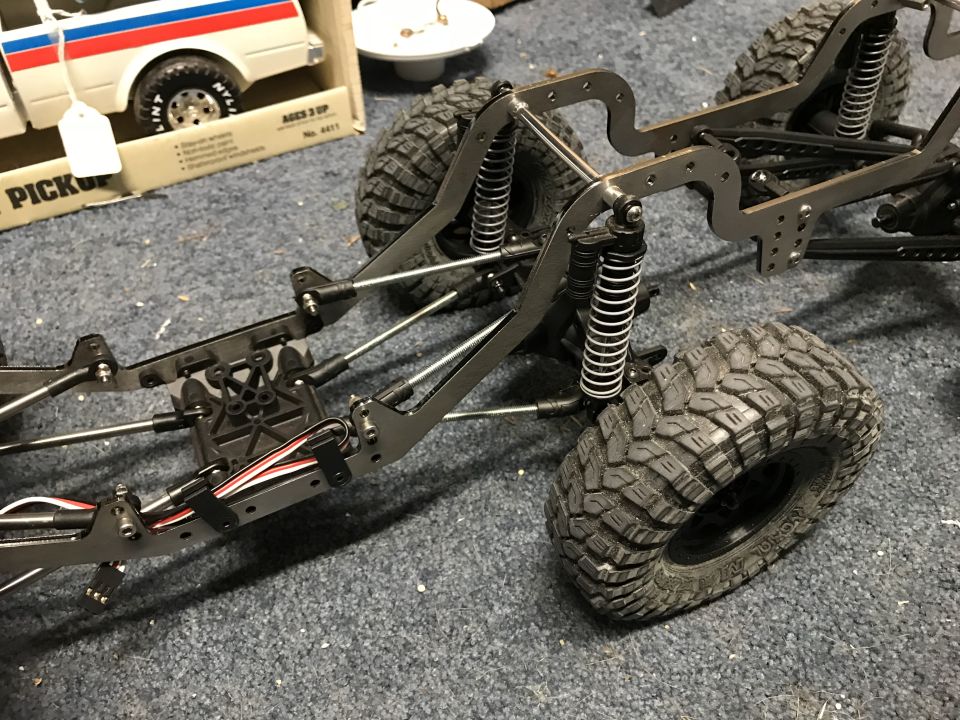 RC crawler chassis with shocks and tires. Box for a toy pickup truck in background