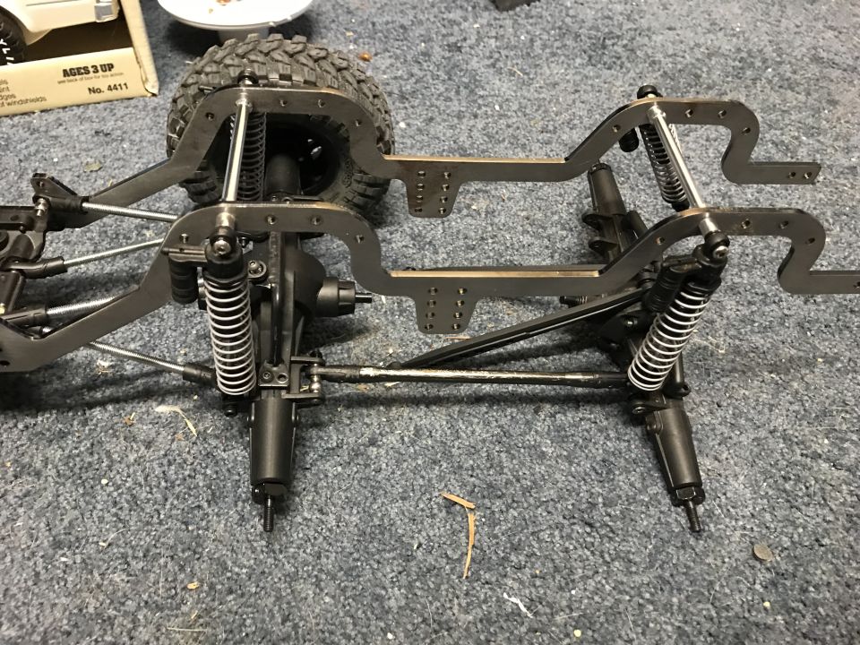 RC car chassis frame with shocks and axles, one tire visible