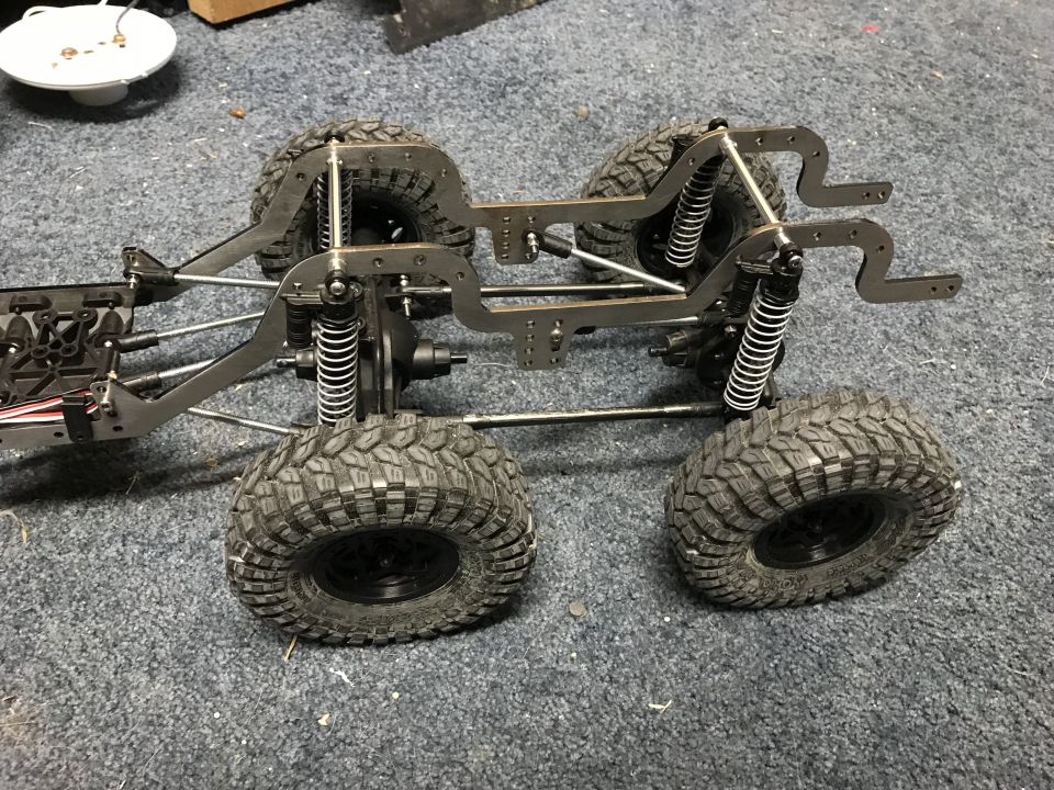 RC crawler chassis with four large, knobby tires and suspension components