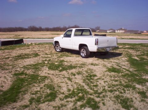 1988 Ford Bronco - A white pickup truck is parked on a dirt lot under a clear blue sky.