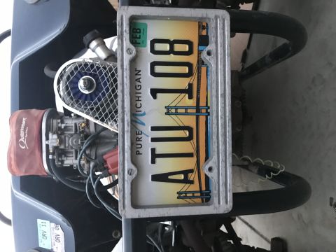 1970 Volkswagen Beetle - Close-up of a motorcycle engine and its Michigan license plate.