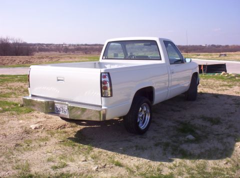 1988 Ford Bronco - This white pickup truck is parked outdoors on a dirt lot under a clear sky.