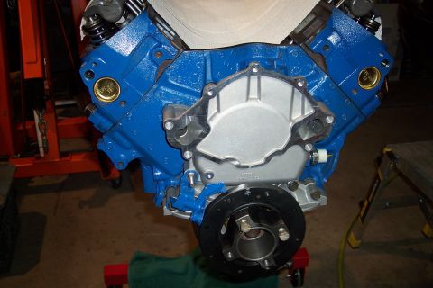 1995 Ford Bronco - A blue V8 engine block is shown with a silver timing cover and black crankshaft pulley, likely undergoing assembly or repair.