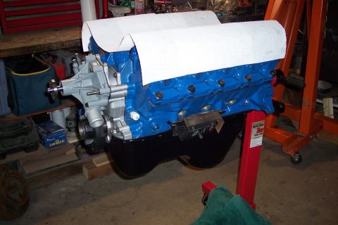1995 Ford Bronco - A blue V8 engine is mounted on a red engine stand, ready for assembly or transport.