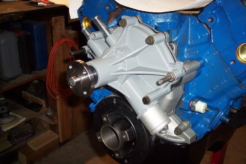 1995 Ford Bronco - Close-up of a gray water pump mounted on a blue engine block, with visible plumbing and bolts.