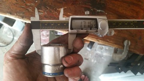 1985 Ford Bronco - A hand holds a socket wrench part while measuring its diameter with digital calipers.